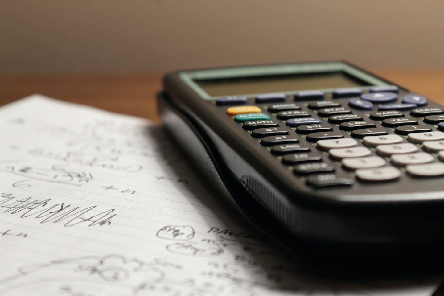 Black graphing calculator and math notes on a desk.